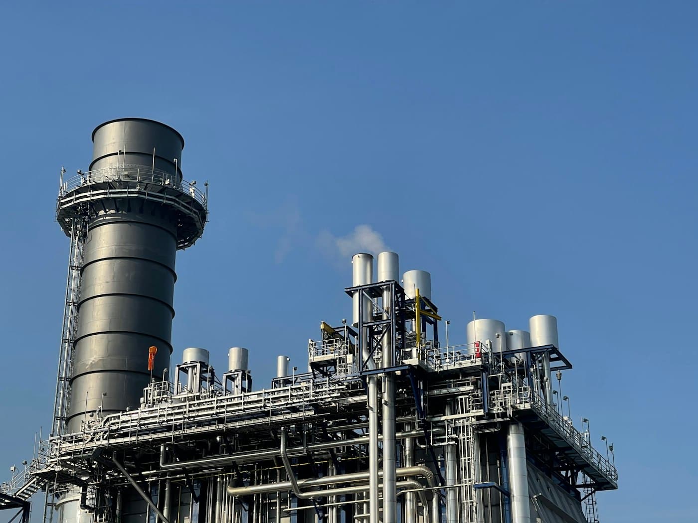 Instalación industrial con chimenea y tuberías de proceso vista desde el exterior