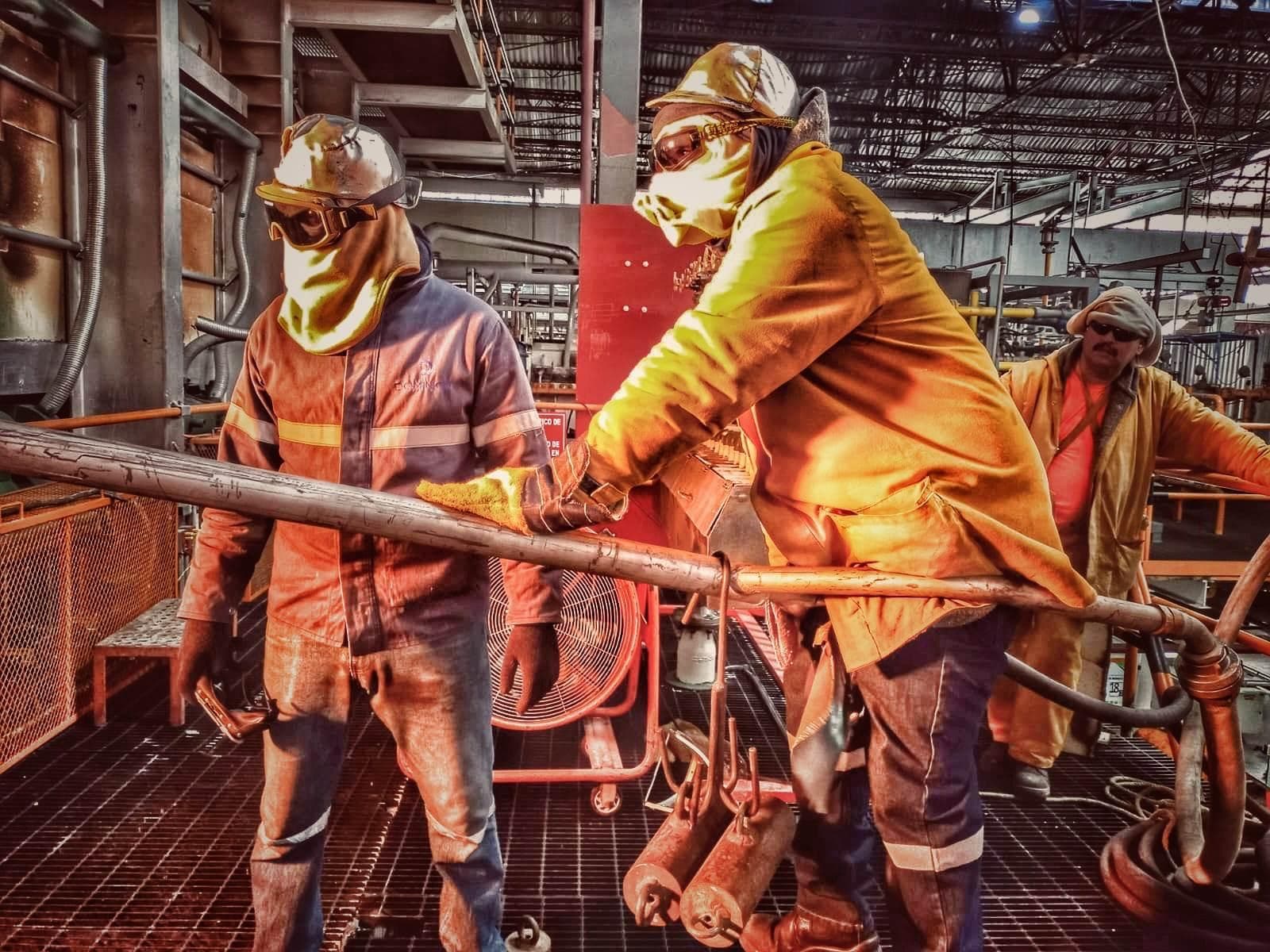 Personal de Grupo VAD con traje aluminizado y equipo de protección operando en planta industrial